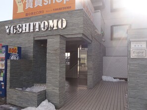 A building with a stone facade and a sign reading "Yoshitomo". - Park Avenue Kokubunji (Koganei)