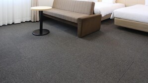 Una habitación de hotel con sofá, una mesita redonda, cama y mesita de noche.