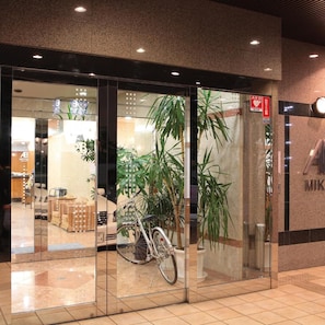 A hotel entrance with glass doors, a bicycle parked inside, and a visible AED sign. - Ab Hotel Mikawa Anjo Honkan (Anjo)