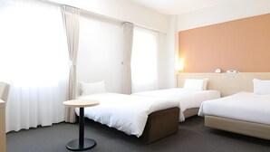 Habitación de hotel con dos camas, una mesita y una mesilla de noche.