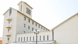 Ein Gebäude mit einem Schild, auf dem "Royal Garden Hotel" steht. Es besitzt einen modernen architektonischen Stil mit einer flachen Dachterrasse und mehreren Balkonen.