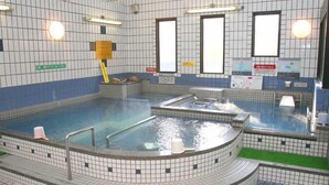 Ein Pool mit mehreren Whirlpools, gefliesten Wänden und einigen Schildern.