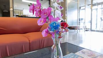 A reception area with a glass vase containing pink and white orchids on a glass table.