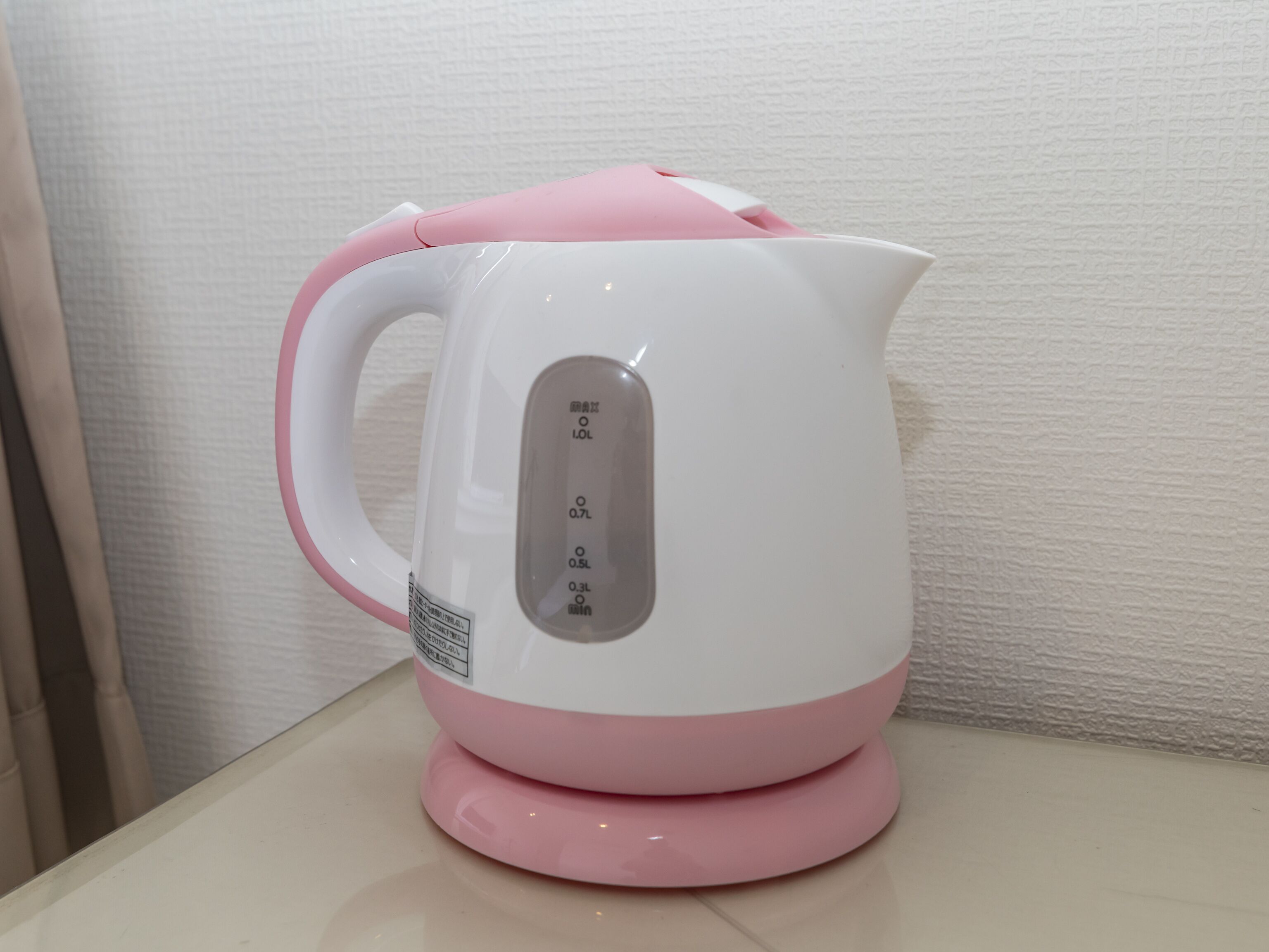 A white and pink electric kettle with measurement markings on the side.