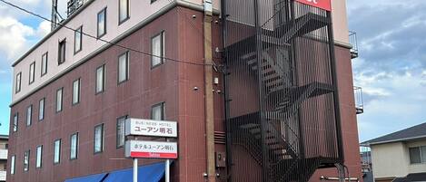 Un hotel de negocios con un llamativo letrero de Tabist en la fachada, varias ventanas y un toldo azul sobre la entrada.