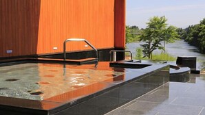 Ein moderner Wellnessbereich mit Whirlpool, kleinem Schwimmbecken und Blick auf einen Fluss.