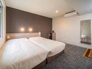 Une chambre d’hôtel avec un lit double, une table de chevet, une commode, une armoire, un miroir et une fenêtre.