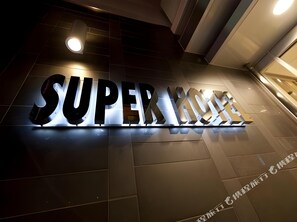 Un grand panneau lumineux avec les mots « SUPER HOME » sur un fond sombre.