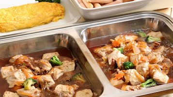 A buffet with various dishes including a large omelette, sausages, and a meat dish with vegetables.