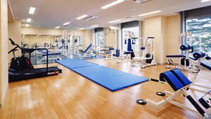 A gym with exercise equipment, a blue mat, and large windows. - Shibetsu Inn Suigetsu (Shibetsu)