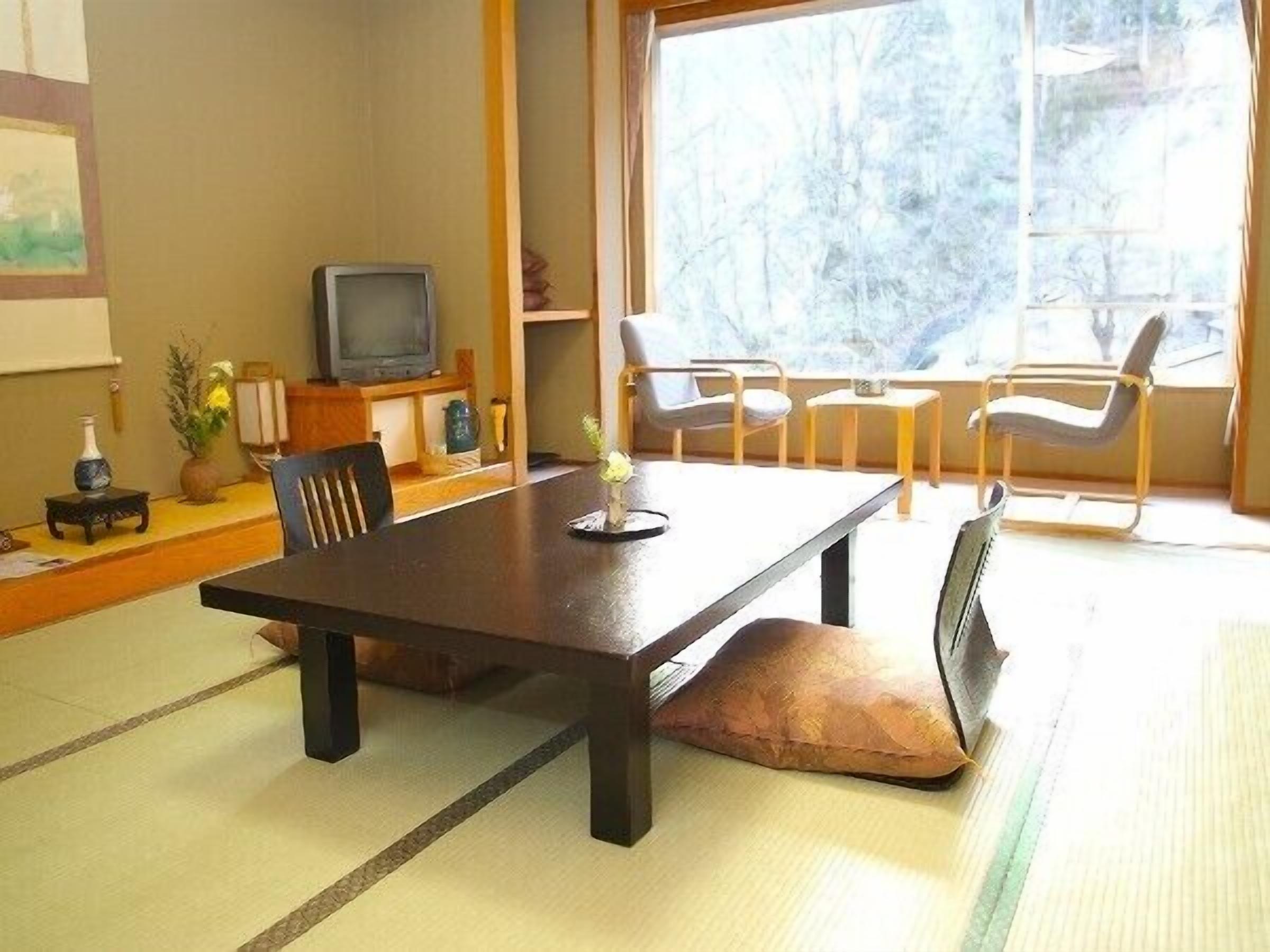 Um quarto tradicional japonês com tatames, uma mesa baixa e uma televisão.