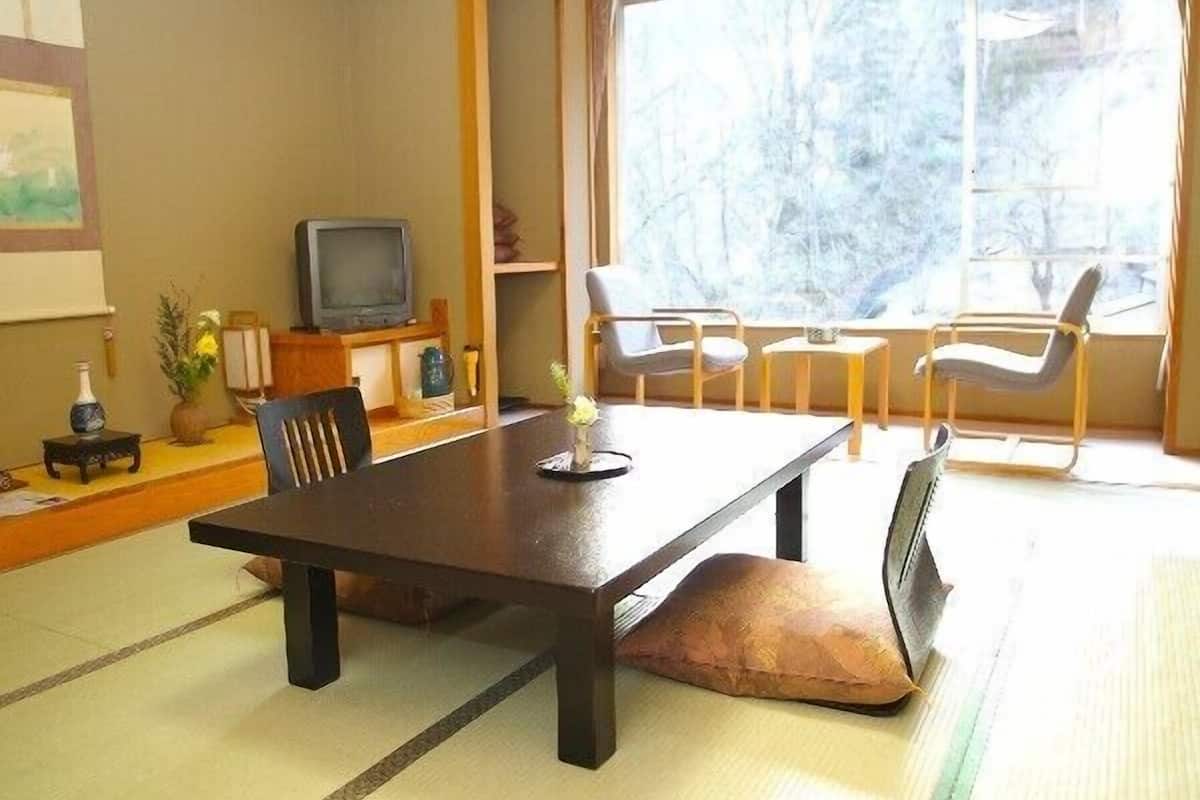 Una habitación tradicional japonesa con suelo de tatami, una mesa baja y un televisor.