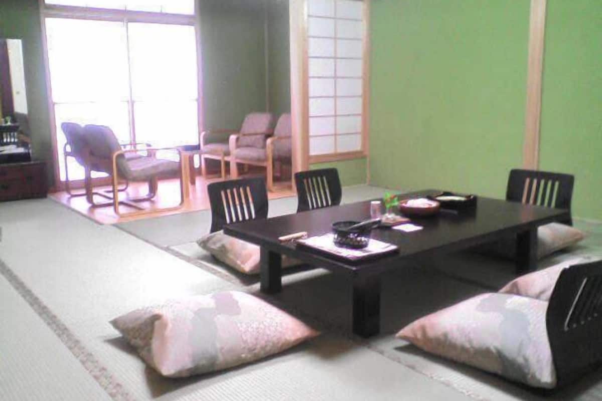 Una habitación con esteras de tatami, una mesa baja, sillas y vistas a una estancia tradicional japonesa.