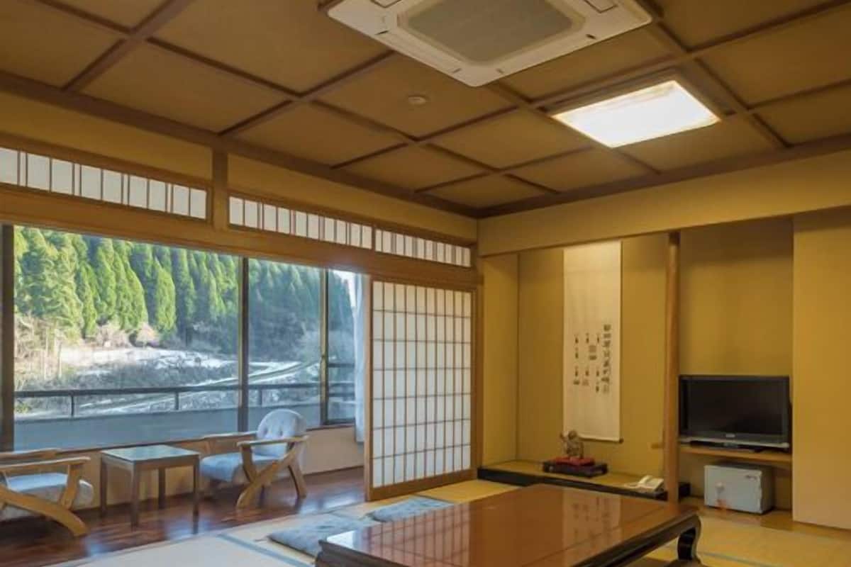 Habitación con tatamis, una mesa de tatamis, televisión y vistas de un río.