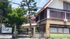 A residential building with a garage, a balcony, and a tree in front. - Okuyama (Shinjo)