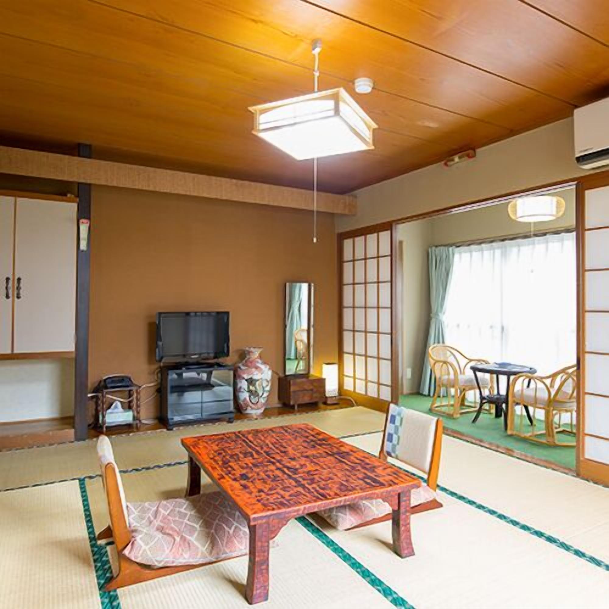 Une pièce de style japonais traditionnel, avec un sol recouvert de tatamis, une petite table en bois et un téléviseur.
