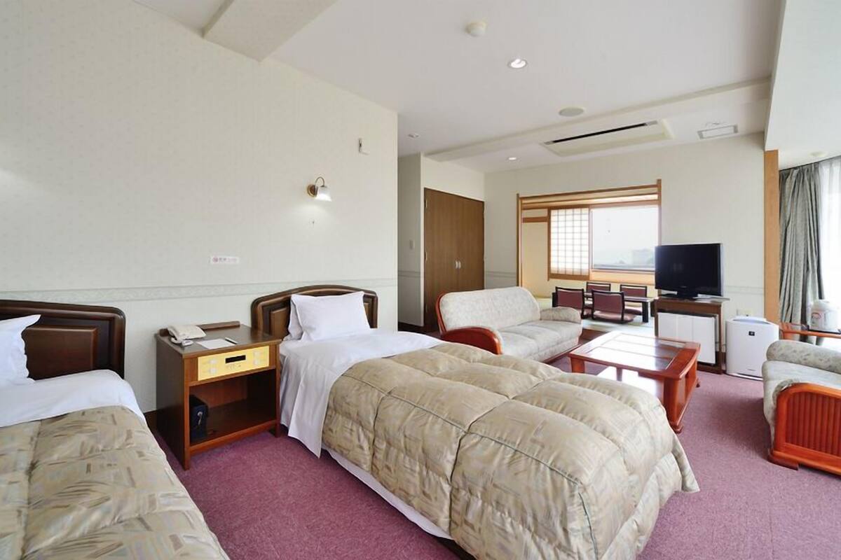 Een hotelkamer met twee bedden, een bank, een televisie en een zithoek.
