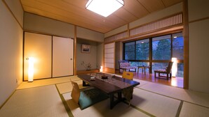 A traditional Japanese room with tatami flooring, a low table, and sliding doors.