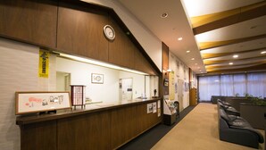 A reception area with a wooden counter, framed artwork, a clock, and a seating area with a sofa.