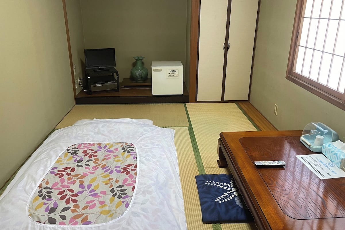 A room with a bed, a wooden table, a TV, and a wardrobe.