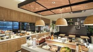 A modern kitchen with wooden cabinets, a central island with various food items, and pendant lighting. - Super Hotel Kofu Showa Inter (Showa)