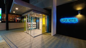 A hotel entrance with a glass facade, a neon sign reading "SUPER HOTEL," and a visible reception area. - Super Hotel Kofu Showa Inter (Showa)