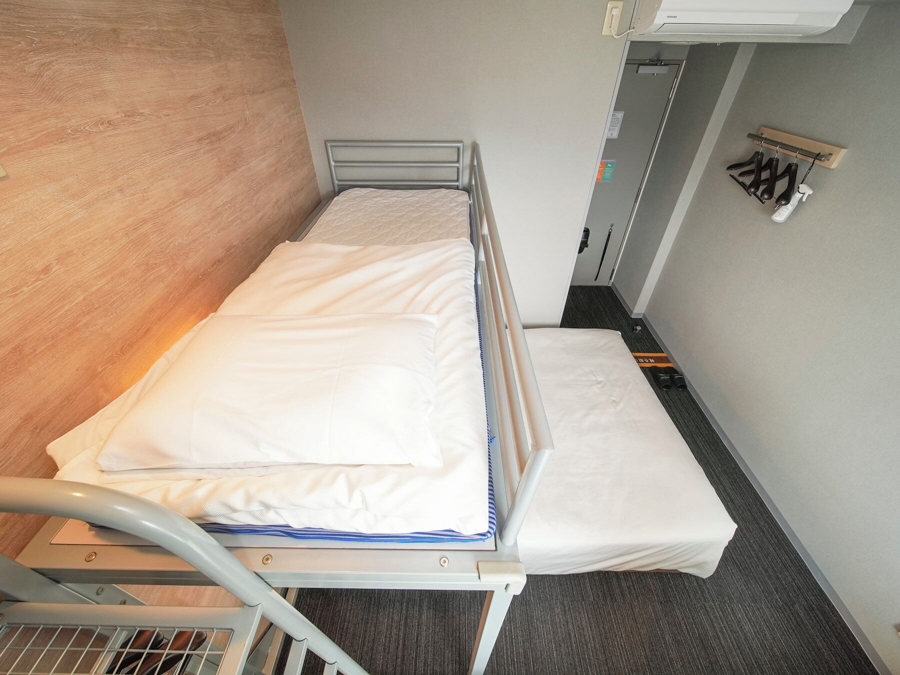 Un lit simple avec un cadre en métal, un matelas blanc et une tête de lit en bois.