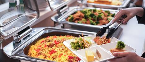 Un bufé con diversos platos, incluyendo arroz, albóndigas y ensaladas.