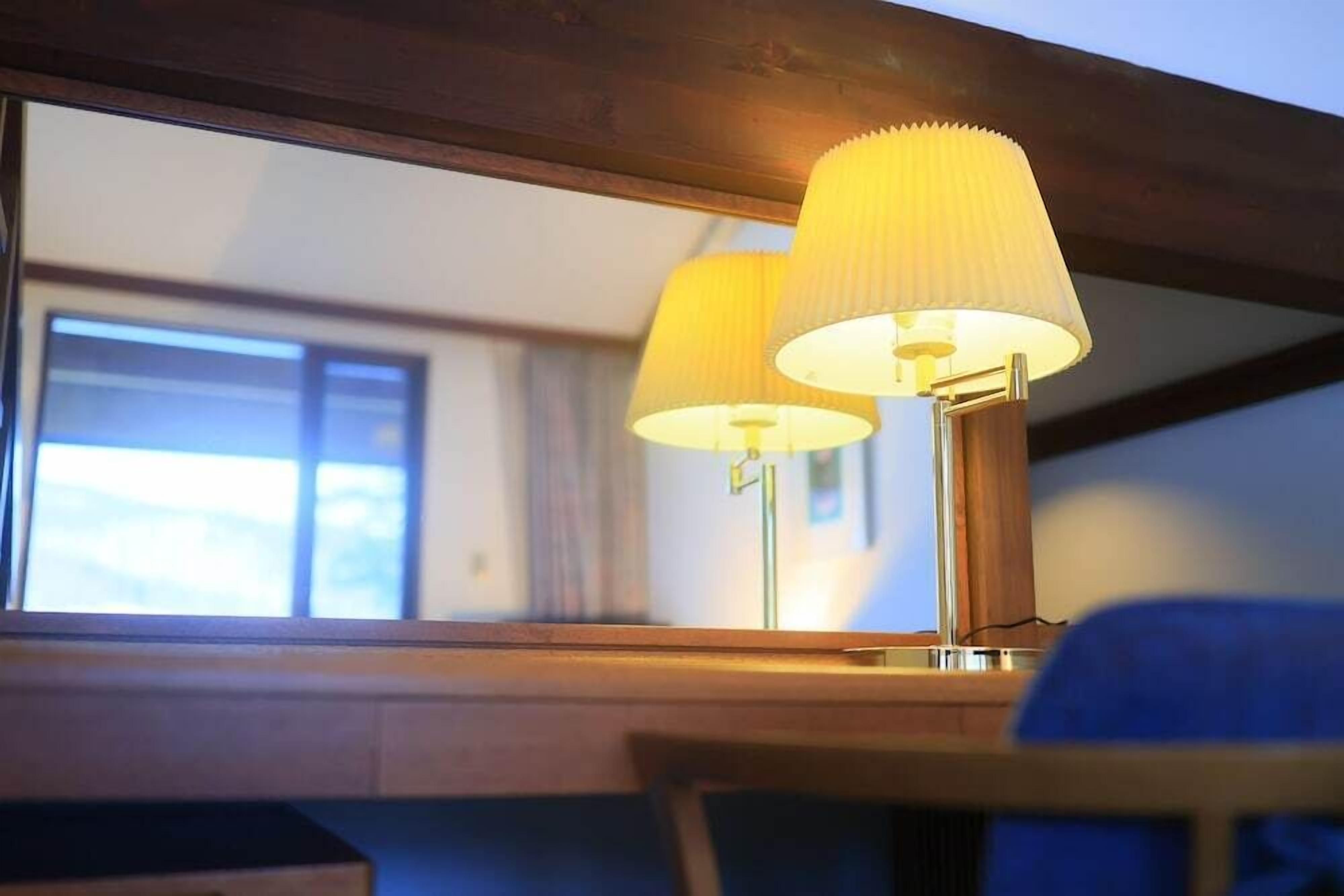 A lamp with a ribbed lampshade on a wooden table.