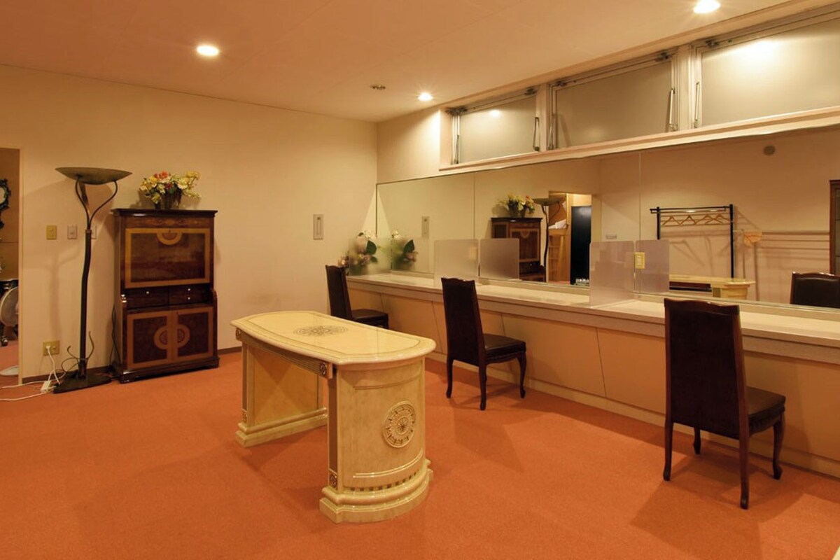 Una habitación con una mesa de comedor, sillas, un armario, un espejo y un reloj en la pared.
