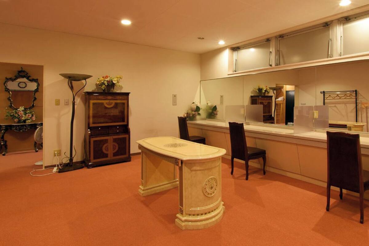 A room with a dining table, chairs, a cabinet, a mirror, and a clock on the wall.