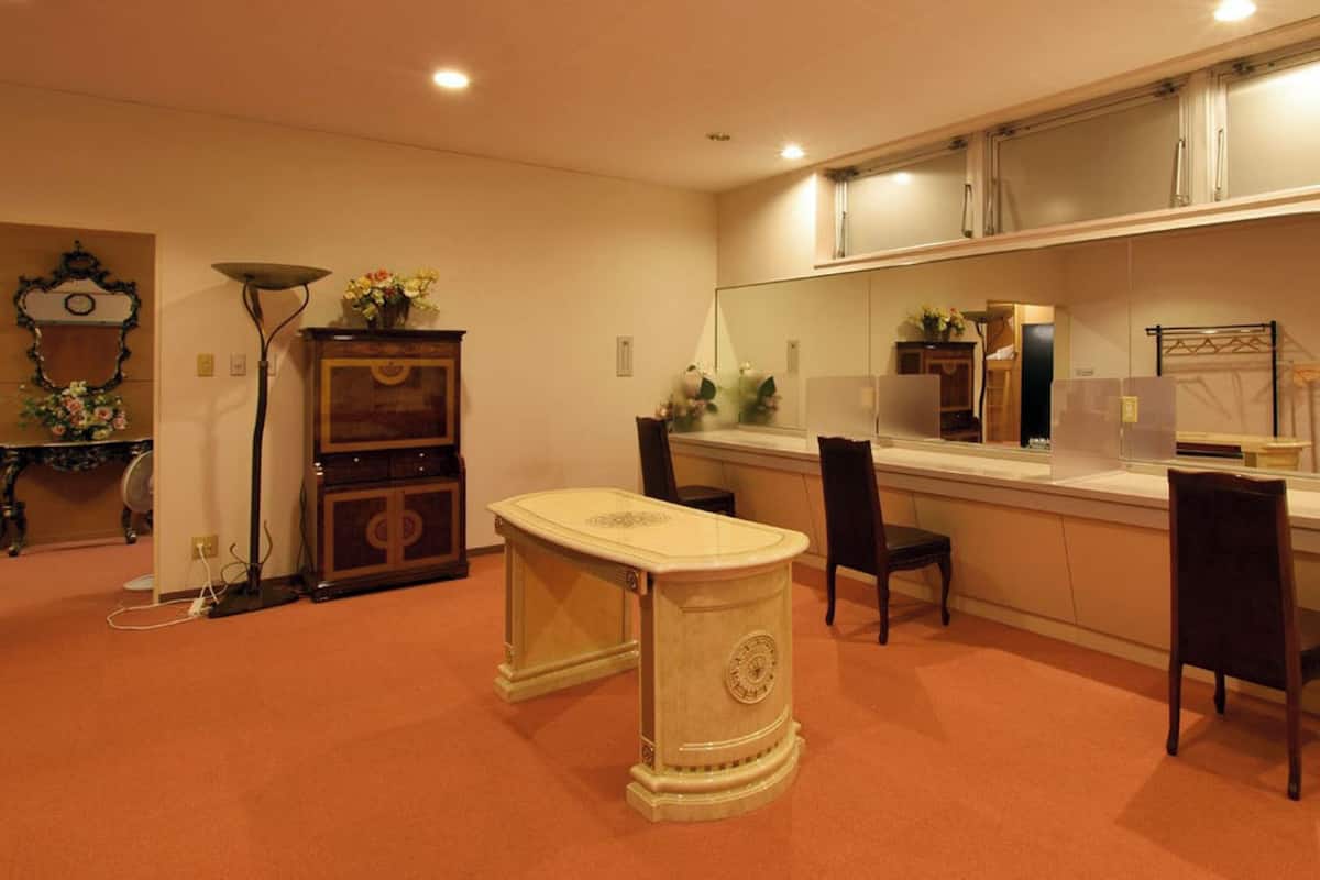 A room with a dining table, chairs, a cabinet, a mirror, and a clock on the wall.