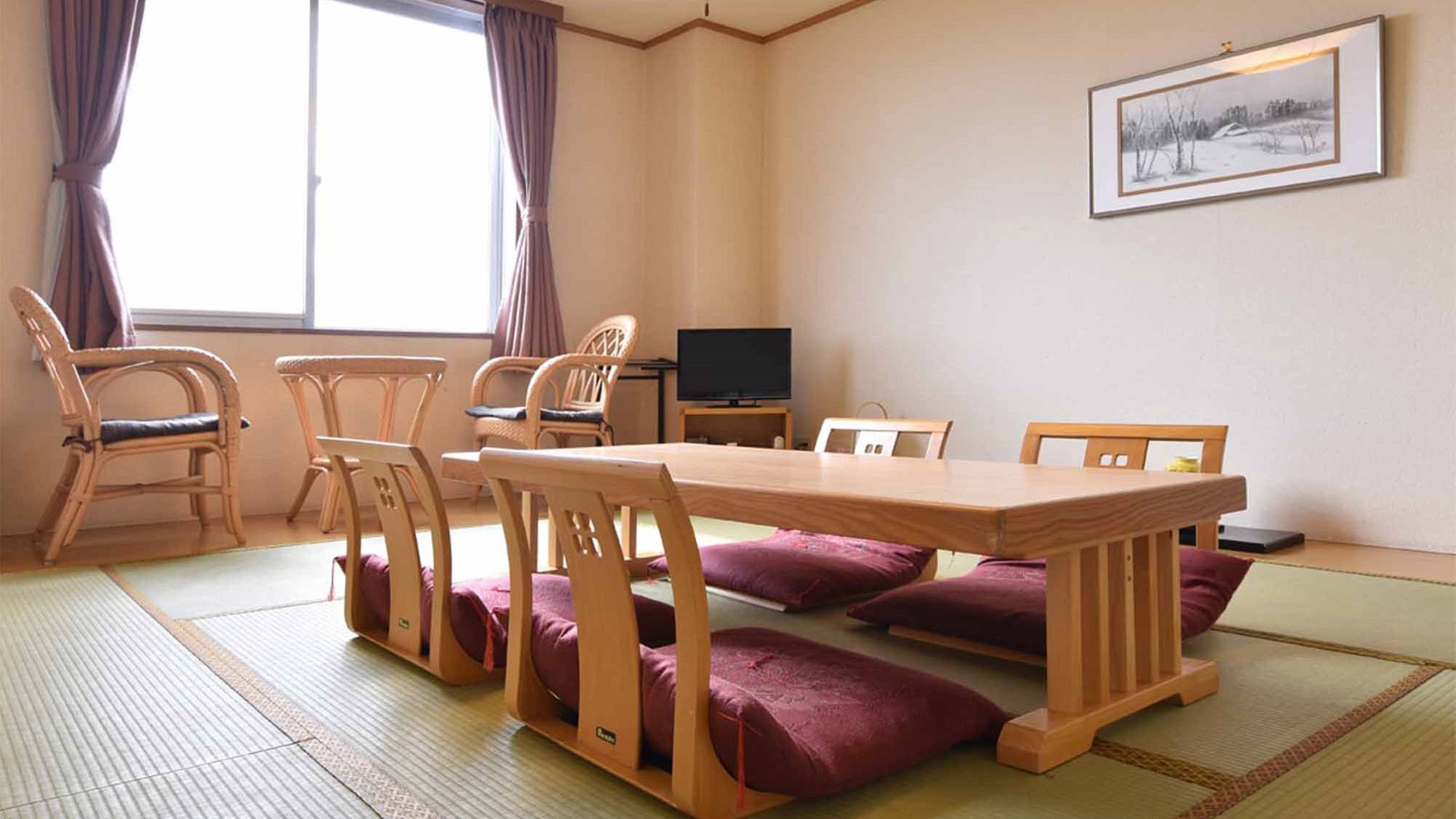 Une pièce de style japonais traditionnel, avec un sol recouvert de tatamis, une table basse, des chaises en bois et un téléviseur.