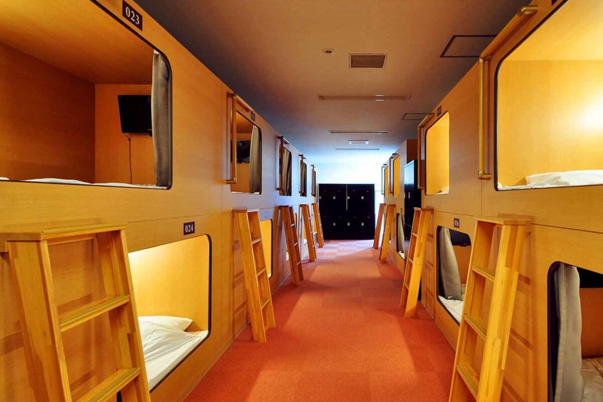 A corridor with bunk beds, each with a number label, and a door at the end.