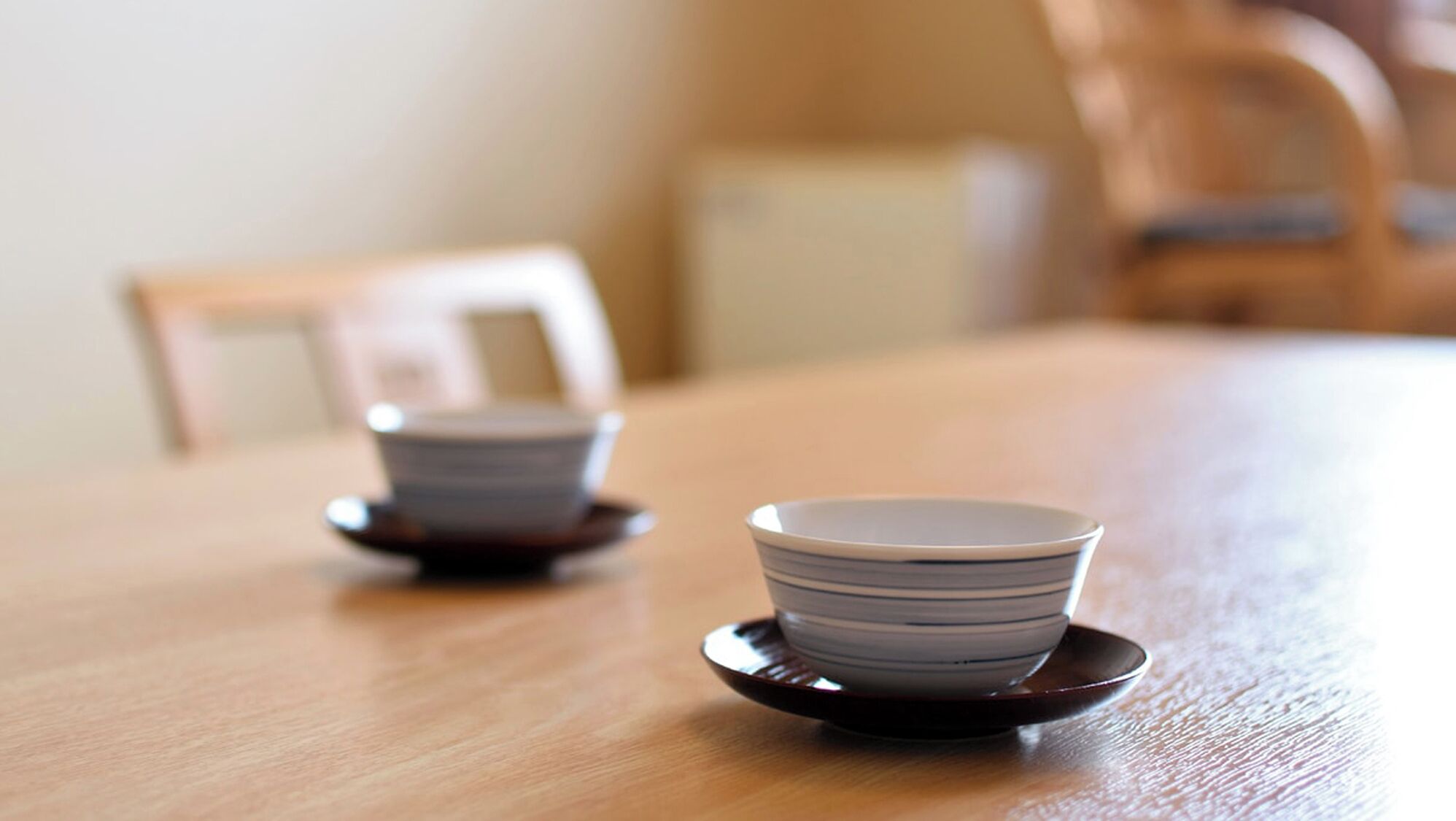 A wooden table with two stacked bowls on saucers.