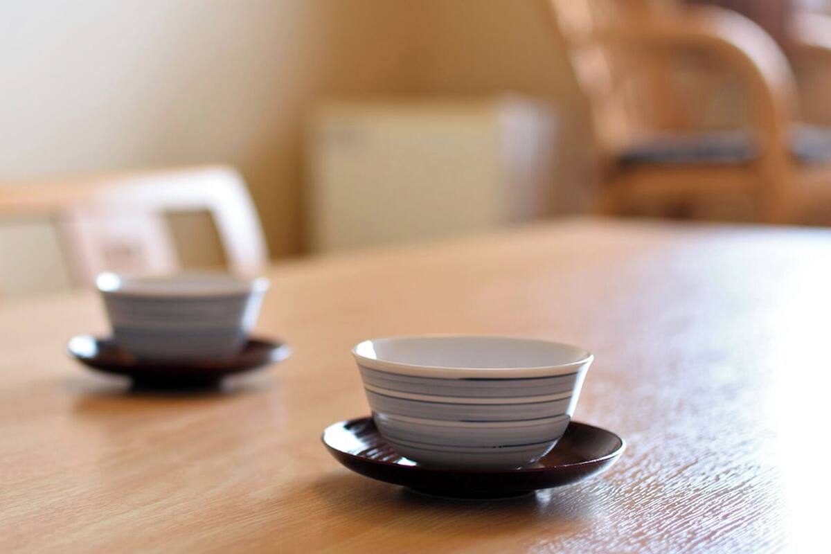 A wooden table with two stacked bowls on saucers.