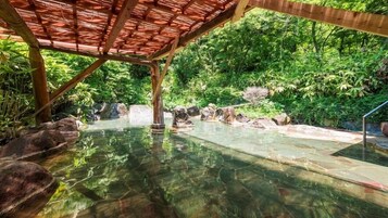 Una piscina cristalina con rocas y una estructura de pérgola de madera.