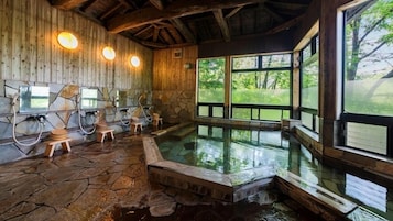 Un área de spa con suelo de piedra, paredes de madera, un ventanal grande y una bañera de hidromasaje.