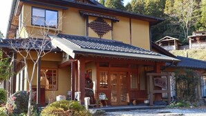 Un edificio tradizionale giapponese con tetto in tegole, porte di legno e un piccolo portico.