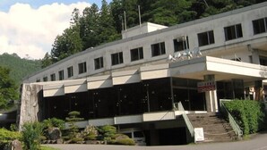 Ein modernes Gebäude mit Flachdach, zahlreichen Fenstern und einer Treppe, die zu einem Eingang führt.