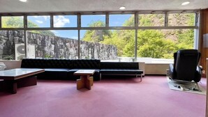 Ein Zimmer mit Steinwand, einer schwarzen Couch, einem Holztisch und einem Massagesessel.