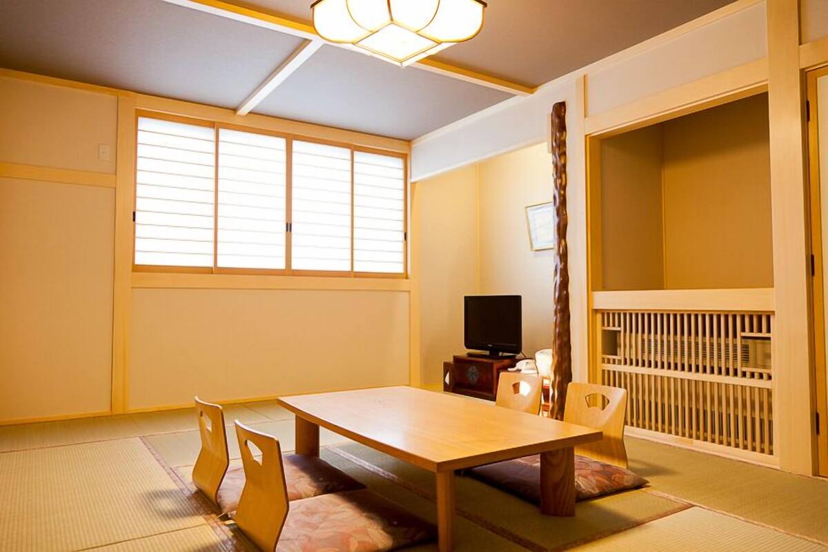 A traditional Japanese room with tatami flooring, a low table, and sliding doors.