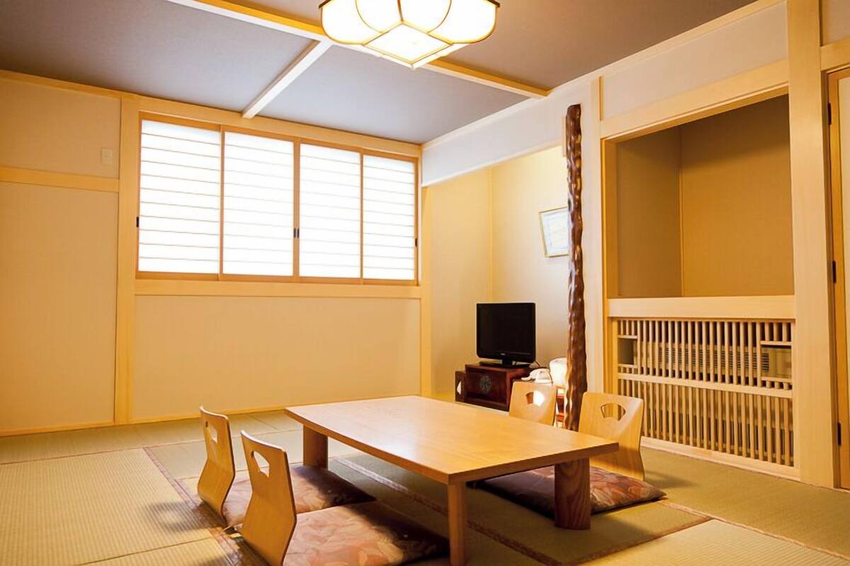 A traditional Japanese room with tatami flooring, a low table, and sliding doors.