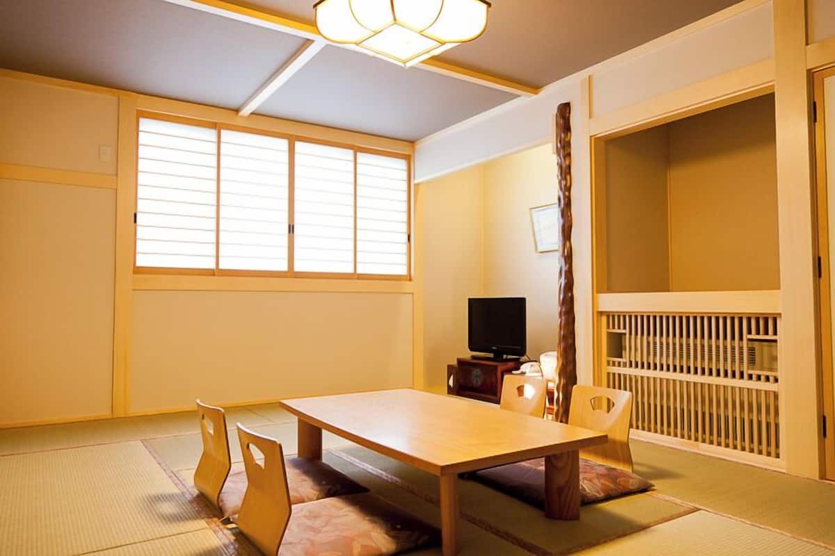 Una habitación tradicional japonesa con suelo de tatami, una mesa baja y puertas correderas.