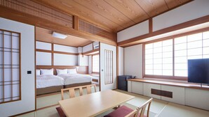 A traditional Japanese-style room with tatami flooring, a low wooden table, a bed with futon mattresses, and sliding doors.