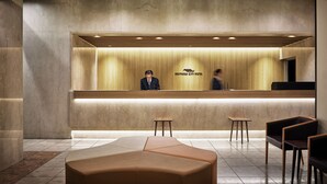 A hotel reception area with a modern design, featuring a reception desk, seating area, and a large, cushioned bench.