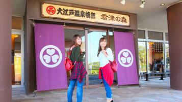 Two women standing in front of a building with a large purple banner and a sign above the entrance.