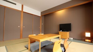 A traditional Japanese room with tatami flooring, a wooden table with cushions, a television, and a cabinet. - Ooedo Onsen Monogatari Kimitsu no Mori (Kimitsu)
