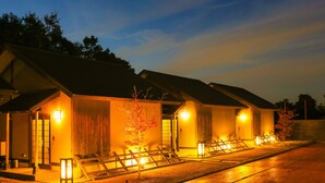 A row of traditional-style buildings with wooden facades and tiled roofs, each with a small porch and a lantern. - Ooedo Onsen Monogatari Kimitsu no Mori (Kimitsu)