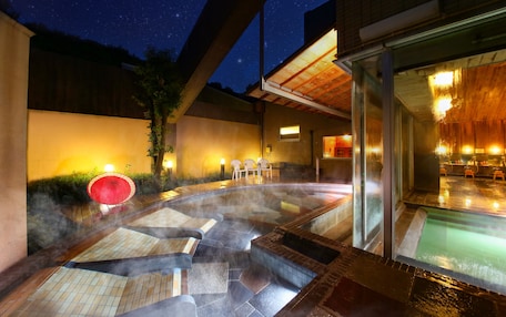 A hot tub area with steam rising, surrounded by a wooden deck and a glass enclosure.